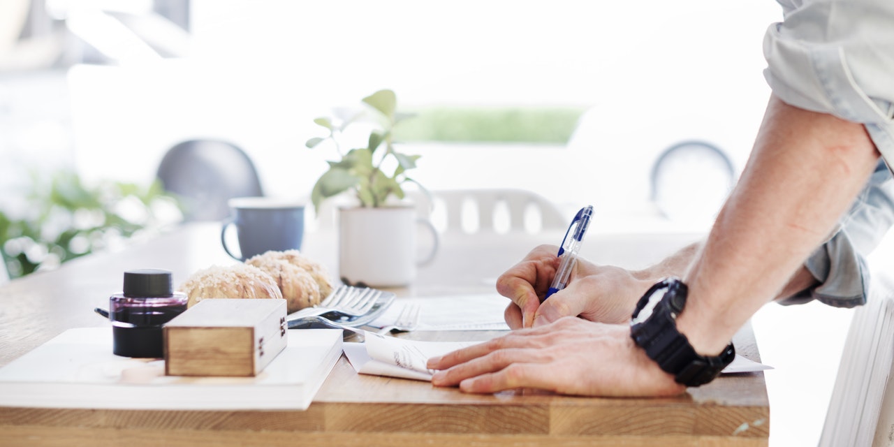 Person writing on notepad refiining their resume