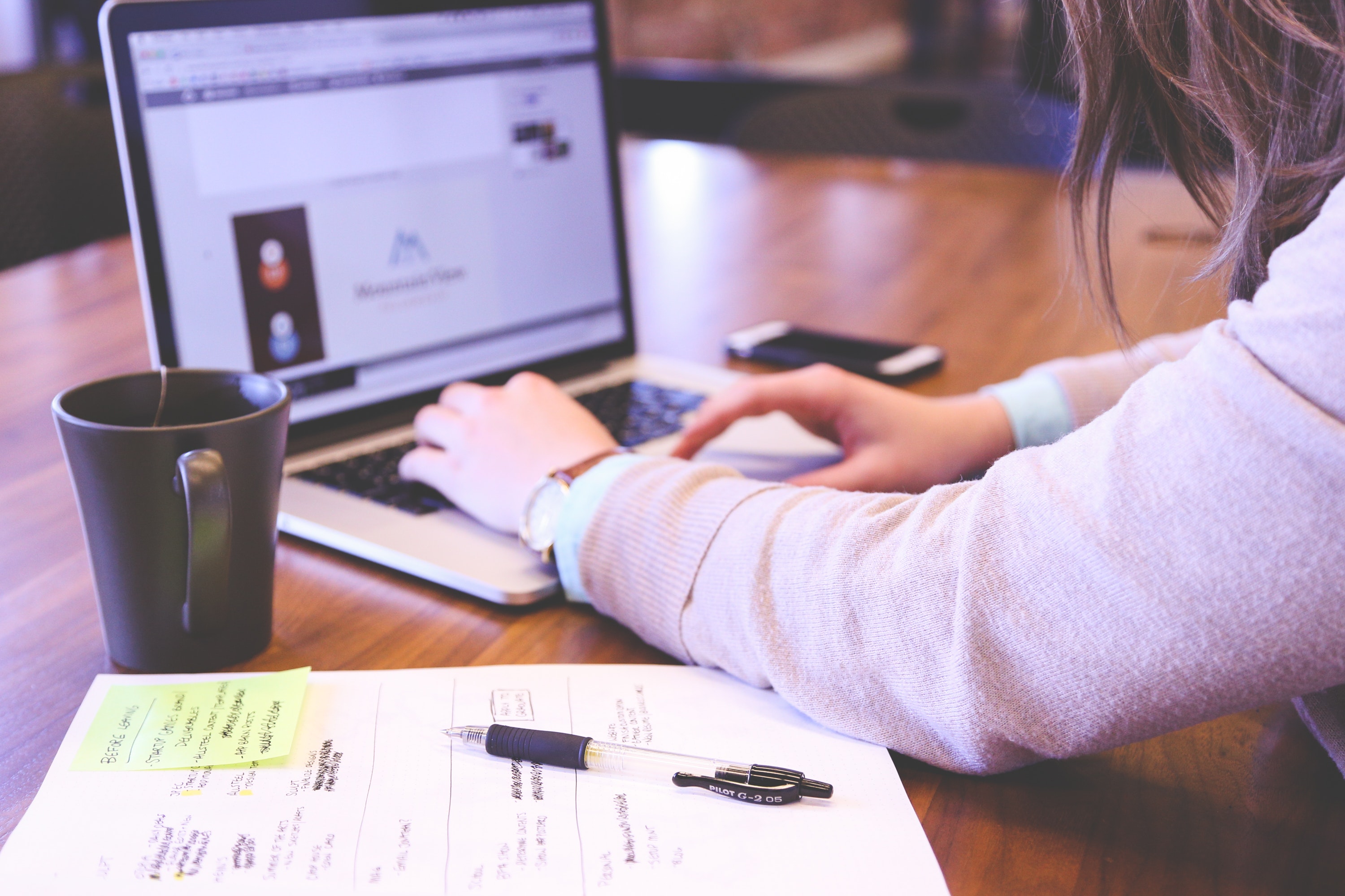 woman on laptop drinking tea with notebook