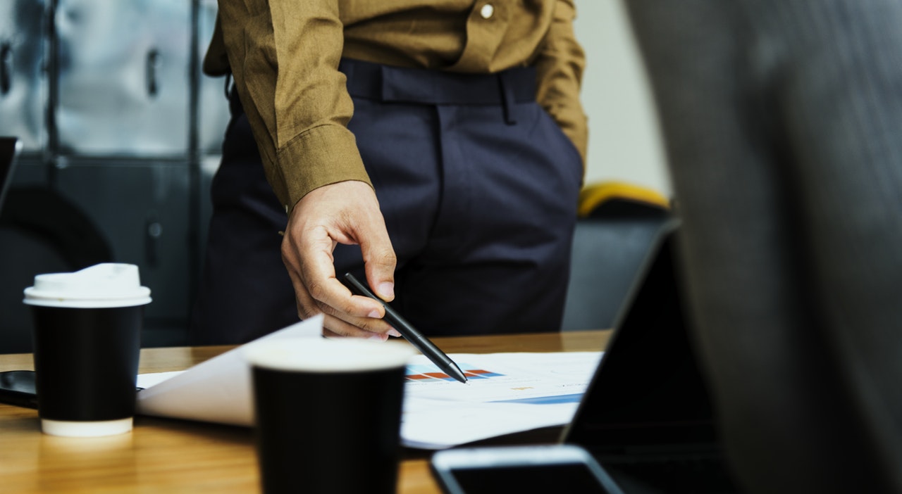 Man in suit with pen pointing at document during meeting