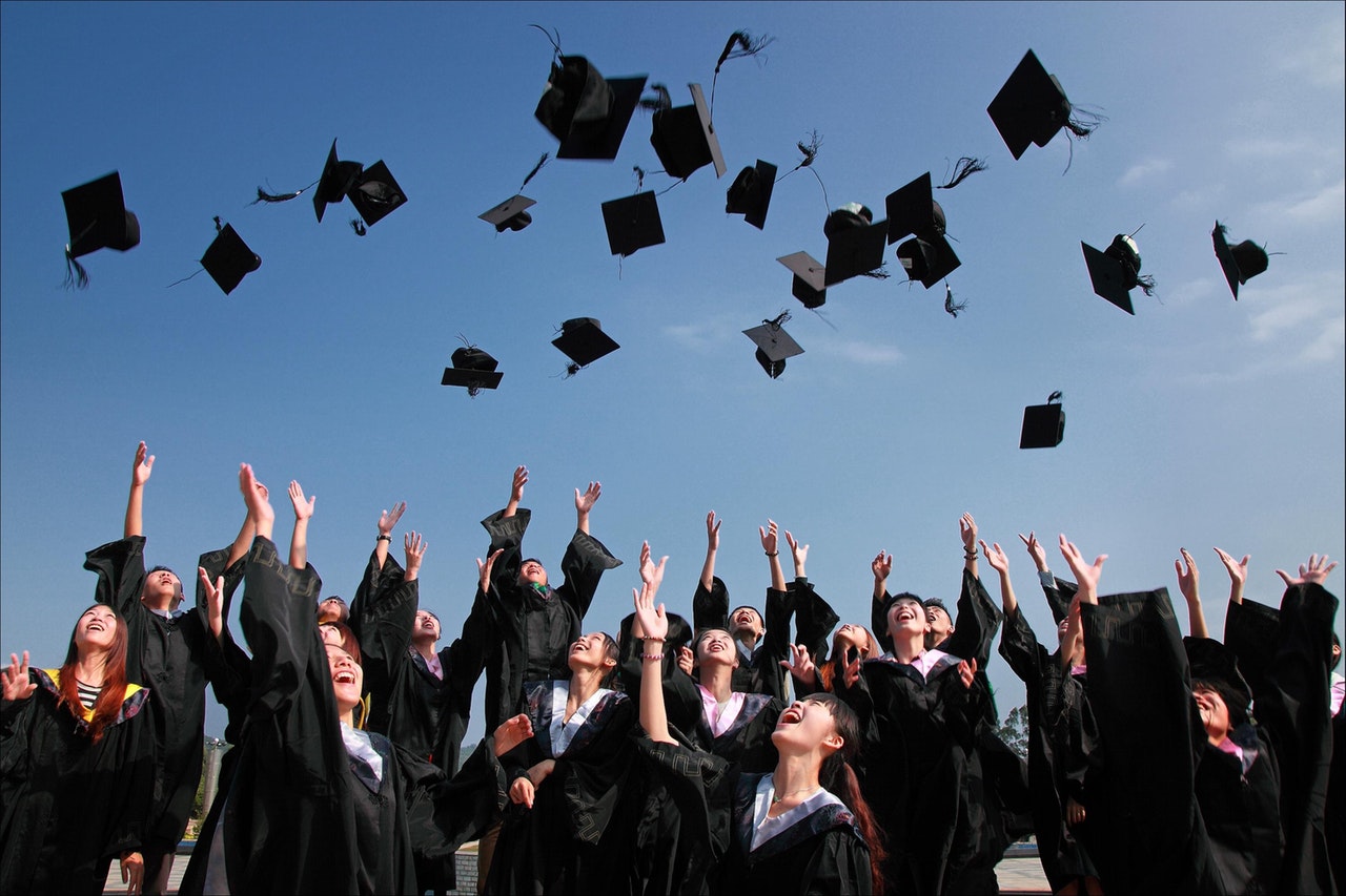 college graduates throwing hats into the air