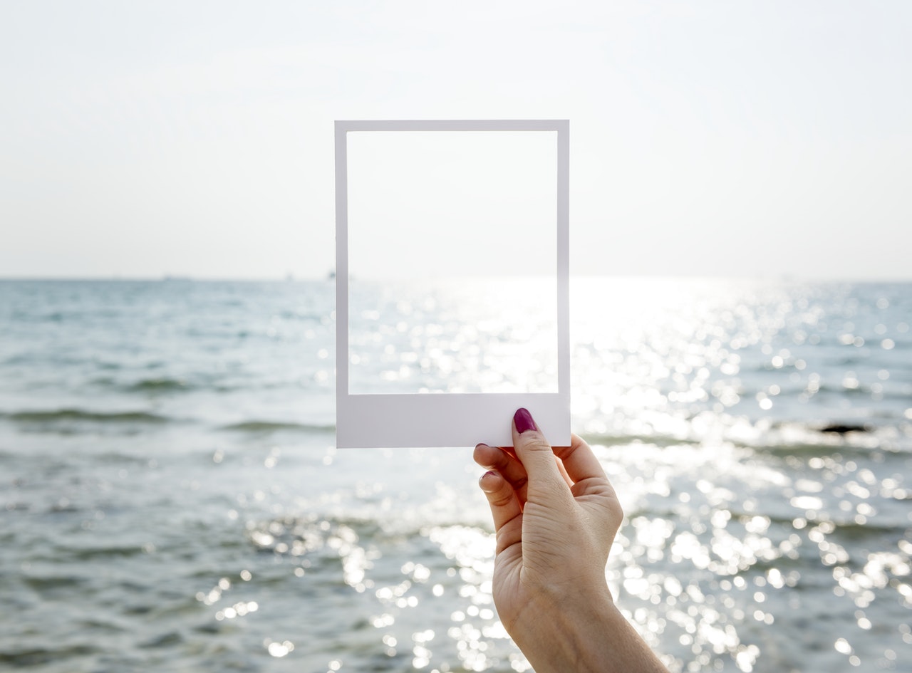 Person holding frame out towards ocean